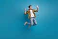 Full size body photo of funny man in air jumping with smartphone makes selfie shows his emotions isolated on blue color Royalty Free Stock Photo