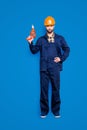 Full size body portrait of handsome attractive repairer in protective hard hat with stubble having equipment in arm