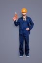 Full size body portrait of handsome attractive repairer in protective hard hat with stubble having equipment in arm