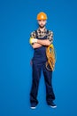 Full size body portrait of virile brutal electrician with bristle in overall, shirt, holding rolled cable in hand Royalty Free Stock Photo