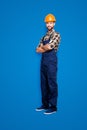 Full size body snap, with legs portrait of cheerful half-turned, handsome repairer in shirt and overall, having his arms