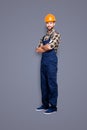 Full size body snap, with legs portrait of cheerful half-turned, handsome repairer in shirt and overall, having his arms