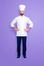 Full size fullbody portrait of attractive harsh chef cook with stubble in beret, holding arms on waist, isolated over