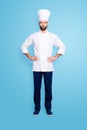 Full size fullbody portrait of attractive harsh chef cook with stubble in beret, holding arms on waist, isolated over