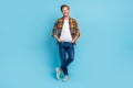 Full size length photo of handsome man dressed plaid shirt jeans standing crossed legs hands in pockets isolated on blue Royalty Free Stock Photo