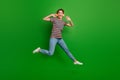 Full size photo of active carefree girl jumping listen new single headphones isolated on green color background