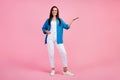 Full size photo of adorable lovely girl dressed blue shirt white trousers arm show object empty space isolated on pink