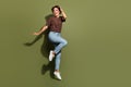 Full size photo of adorable pretty graceful woman dressed brown t-shirt pants flying hand on head isolated on khaki