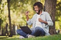 Full size photo of afro american attractive crazy man sit in park grass tree raise fists win computer outside in