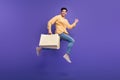 Full size photo of attractive young man running fast hold shopping bags wear trendy yellow clothes isolated on violet Royalty Free Stock Photo