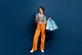 Full size photo of attractive young woman shopping bags device dressed stylish flared pants clothes isolated on blue Royalty Free Stock Photo