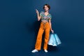 Full size photo of attractive young woman shopping bags point empty space wear trendy flared pants isolated on dark blue Royalty Free Stock Photo