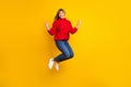 Full size photo of blond optimistic lady jump hands fists wear red sweater jeans sneakers isolated on bright yellow Royalty Free Stock Photo