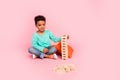 Full size photo of charming small boy play jenga game playroom wooden tower dressed stylish cyan outfit isolated on pink Royalty Free Stock Photo