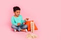 Full size photo of charming small boy play kindergarten wooden tower wear trendy aquamarine outfit isolated on pink Royalty Free Stock Photo