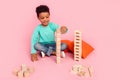 Full size photo of charming small boy play wooden cubes tower wear trendy aquamarine outfit isolated on pink color Royalty Free Stock Photo