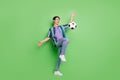 Full size photo of cheerful young positive active man play football game smile isolated on green color background