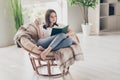 Full size photo of concentrated girl read book sitting on wicker chair with coffee cup wear white t-shirt in house Royalty Free Stock Photo