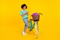 Full size photo of cute millennial lady near bicycle look telephone wear t-shirt jeans shoes bag isolated on yellow Royalty Free Stock Photo