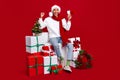 Full size photo of delighted excited guy sit pile stack festive giftbox raise fist hold loudspeaker isolated on red