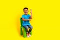 Full size photo of diligent schoolboy wear blue t-shirt sit on chair raising arm up answer question  on vivid Royalty Free Stock Photo