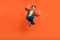 Full size photo of excited crazy smiling male jumping raise fists in victory triumph isolated on orange color background
