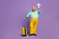 Full size photo excited man big abdomen hold papercard plane travel abroad weekend touch yellow suitcase wear shine