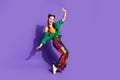 Full size photo of funny adorable woman dressed green shirt vintage pants stand on tiptoes dancing isolated on purple