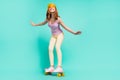 Full size photo of funny blond teenager girl go skate wear cap top pants on teal color background