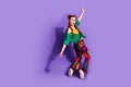 Full size photo of girlish woman dressed green shirt vintage pants stand on tiptoes look empty space isolated on purple