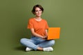 Full size photo of good mood cheerful woman wear t-shirt in glasses sit on floor with laptop working isolated on khaki Royalty Free Stock Photo