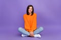 Full size photo of gorgeous young girl sitting floor crossed legs dressed stylish knitted orange look isolated on purple Royalty Free Stock Photo