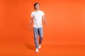 Full size photo of happy positive cheerful man look empty space walk good mood isolated on orange color background