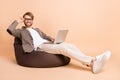 Full size photo of happy positive smiling handsome businessman sit chair work in laptop isolated on beige color Royalty Free Stock Photo