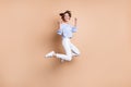 Full size photo of happy victorious young woman jump up air raise fists winner isolated on pastel beige color background