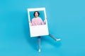 Full size photo of impressed pretty girl fooling around with big white snapshot frame isolated on blue color background