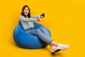 Full size photo of impressed woman striped sit on armchair astonished staring hold joystick play game isolated on yellow