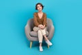 Full size photo of minded creative nice girl sit cozy chair look empty space isolated on blue color background