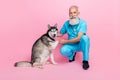 Full size photo of nice positive good mood doctor wear blue uniform sitting hand hold husky paw isolated on pink color