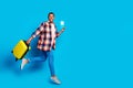 Full size photo of nice young man suitcase tickets jump empty space wear shirt isolated on blue color background Royalty Free Stock Photo