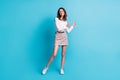 Full size photo of optimistic brunette girl stand dance wear shirt skirt sneakers isolated on teal background Royalty Free Stock Photo