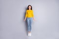 Full size photo of optimistic brunette nice lady jump wear yellow sweater jeans sneakers isolated on grey color Royalty Free Stock Photo