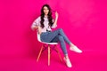 Full size photo of optimistic brunette nice lady sit blow kiss wear jacket jeans sneakers isolated on pink background