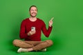 Full size photo optimistic guy wear red shirt sit with smartphone look directing at promo empty space isolated on green