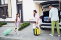 Full size photo of optimistic nice family pack baggage in car wear casual cloth near home outdoors