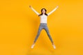 Full size photo of optimistic nice girl jump wear sweater jeans sneakers isolated on yellow color background Royalty Free Stock Photo