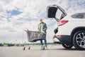 Full size photo of pensioner man shopping cart loading groceries car trunk mall parking black friday store