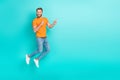 Full size photo of pleasant handsome man muscular beard wear orange t-shirt jeans directing empty space isolated on teal