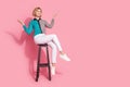 Full size photo of pretty girl model chair raise hands look empty space wear trendy striped cyan outfit isolated on pink