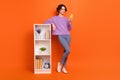 Full size photo of pretty nice lady use gadget telephone stand near book shelf isolated on orange color background